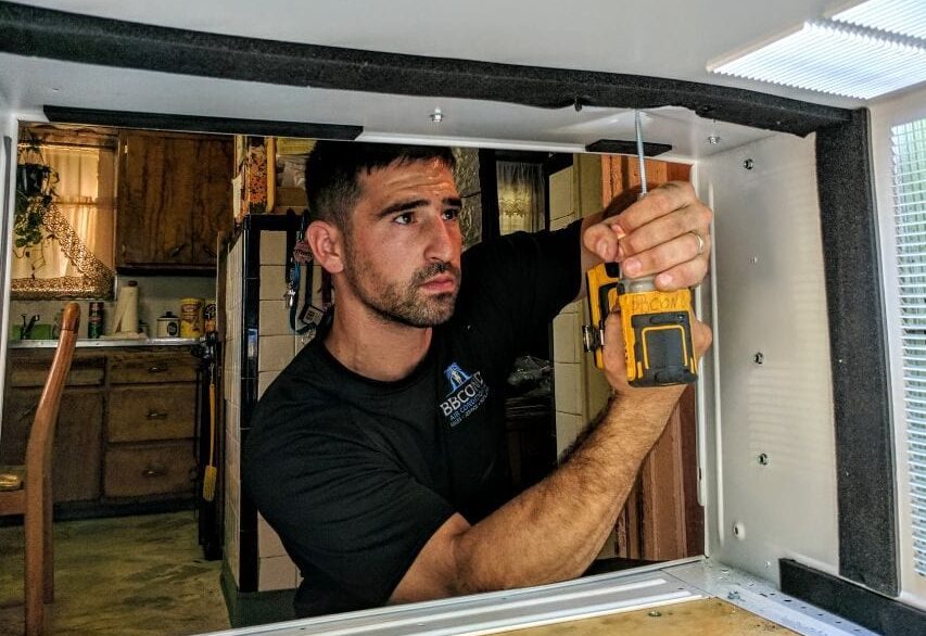 A window AC technician installing