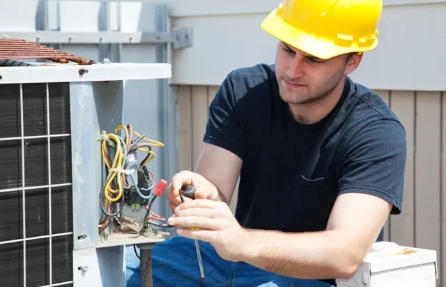 A technician repairing a rooftop condenser unit