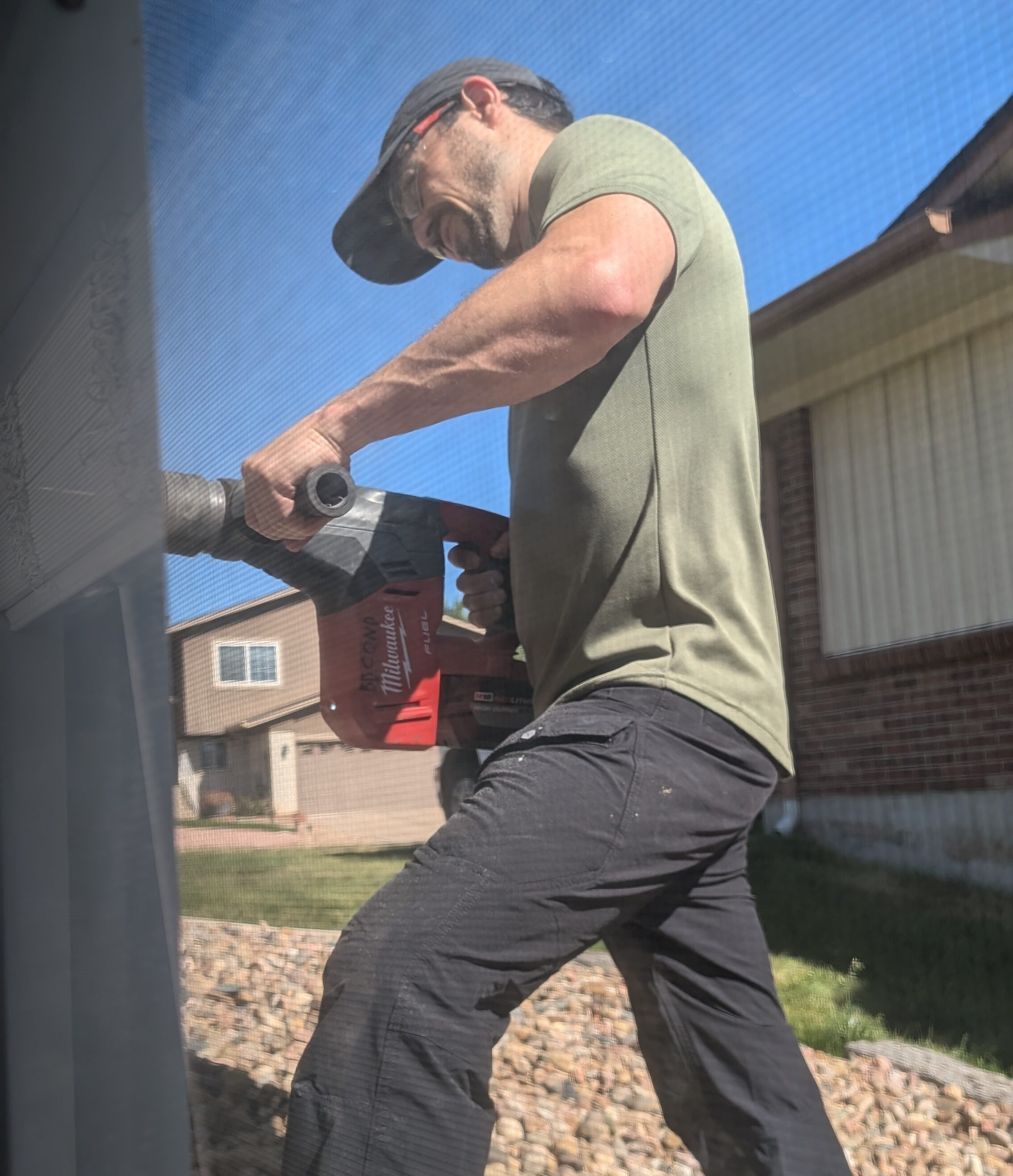 A tech from Brooklyn's Best AC drilling a hole to install a mini-split